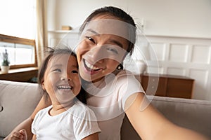 Close up smiling Asian mother and little girl taking selfie