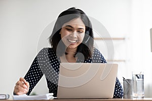 Close up smiling Asian woman wearing headset looking at screen