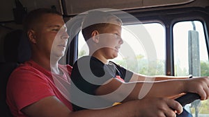 Close up of smiling boy holds the steering wheel sitting on lap of daddy and learning to operate a car. Happy father