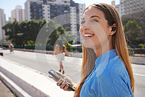 Close-up of smiling Brazilian girl listening music with her earbuds in Sao Paulo, Brazil photo