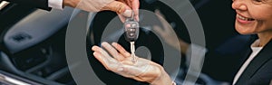 Close up of smiling business woman in suit receiving car keys to new vehicle