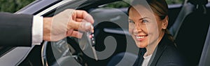 Close up of smiling business woman in suit receiving car keys to new vehicle