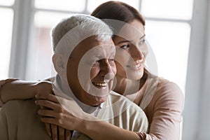 Close up smiling dreamy elderly man and young woman hugging