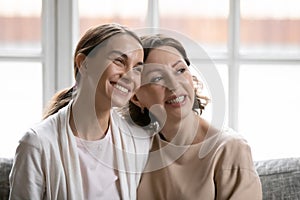 Close up smiling dreamy grownup daughter and mother dreaming together