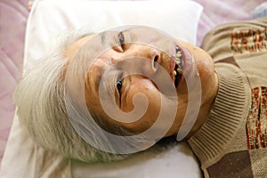 Close-up of the smiling face of an elderly senior woman resting in a nursing bed