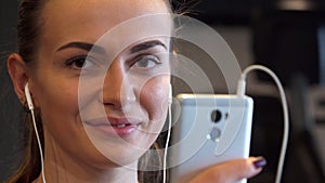 Close-up of a smiling girl face that switches something in the phone