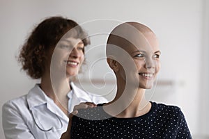 Close up smiling hairless woman with doctor looking to aside