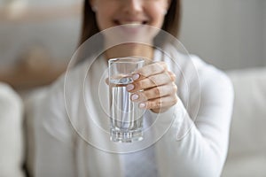 Close up smiling healthy young girl holding glass of pure aqua.