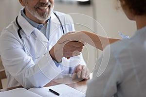 Close up of smiling male doctor and patient handshake