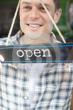 Close Up Of Smiling Male Small Business Owner Turning Around Open Sign On Shop Or Store Window Or Door