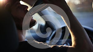 Close-up of smiling man driving the car and drinking water from steel thermo bottle, sunlight effect of sunset. Say No to PLASTIC.