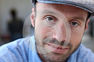 Close up of a smiling man in newsboy hat looking to camera