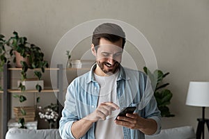 Close up smiling man using phone, browsing apps, having fun