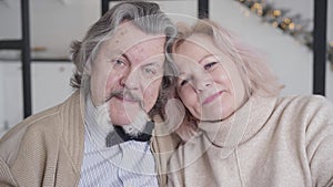 Close-up of smiling mature man and woman looking at camera. Portrait of happy Caucasian senior couple resting on