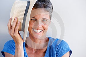 Close up smiling mature woman with hat against white wall