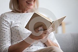 Close up smiling mature woman reading interesting book