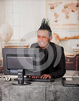 Close up of smiling office punk worker wearing a suit with a crest, working in a computer, in a blurred background