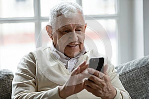 Close up smiling older man using phone, looking at screen