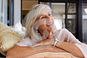 Close up smiling older woman sitting on sofa at home