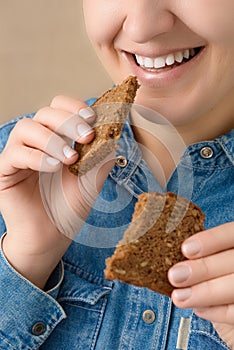 Close-up of a smiling pretty Caucasian woman holding pieces of bread in her hands. Front three-quarter view. Low angle view.
