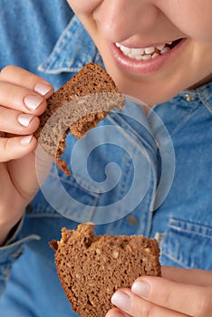 Close-up of a smiling pretty Caucasian woman holding pieces of bread in her hands. Front three-quarter view. View from above.