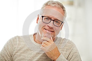 Close up of smiling senior man in glasses thinking