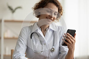 Close up smiling woman doctor making video call, holding smartphone