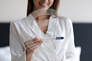 Close up smiling woman holding pregnancy test, satisfied by result