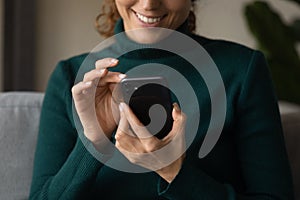 Close up smiling woman holding smartphone, typing on screen