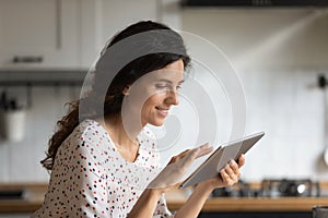 Close up smiling woman looking at tablet screen, typing message