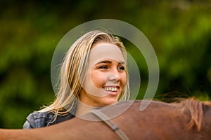 Close-up of smiling woman patting her arabian horse with grass in the field