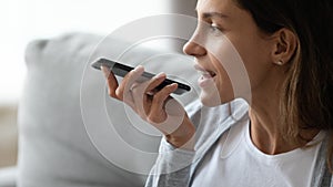 Close up smiling woman recording voice message, holding phone
