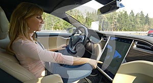 CLOSE UP Smiling woman setting up the navigation in her high tech autonomous car