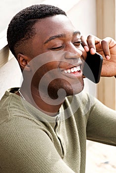 Close up of smiling young african american man talking on phone outdoors