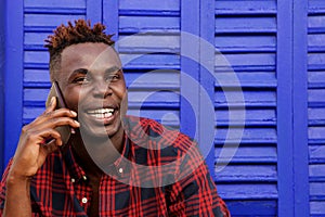 Close up smiling young afro american can man using mobile phone