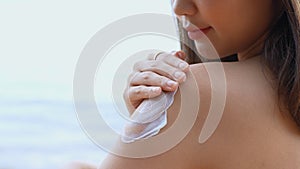 Close up Smiling young asian woman applying a sunscreen lotion on shoulder her skin on a seaside beach tropical resting and relaxa