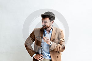 Close up Smiling Young Businessman making faces Wearing Eyeglasses, Looking at the Camera Against Gray Wall