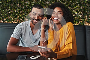 Young couple sharing earphone for listening music on mobile phon