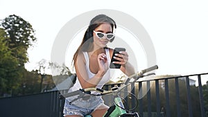 Close up of smiling young cuddy woman in headphones sitting on the bike and listening music