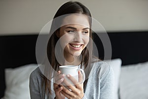 Close up smiling young woman holding white cup of tea