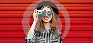 Close up of smiling young woman photographer with film camera over red