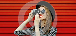 Close up of smiling young woman photographer with film camera over red