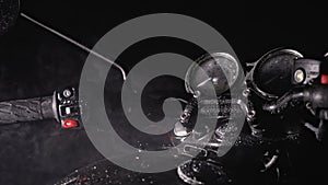 Close-up with smoke or steam of steering wheel, dashboard and fuel tank of retro styled black motorcycle at night