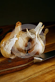 Close up of smoked garlic on a chopping board with knofe