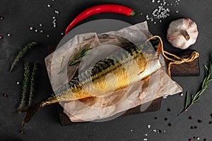 Close-up smoked golden trout fish with vegetables on a black background top view, concept of fish market