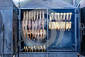 Close up of smokers or roasting ovens with different types of fish being smoked