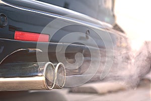 Close up of smoky dual exhaust pipes from a starting diesel car.