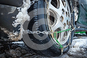 Close-up of snow chain on wheel with friction tire. The concept of safety on snowy roads.