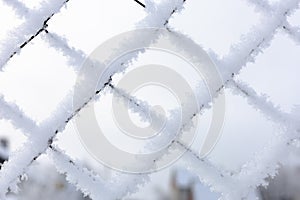 Close-up of snow covered mesh net with bright blue sky in background confining restricted area. Exile to Siberia photo