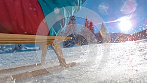 CLOSE UP: Snowflakes glisten in the winter sunshine as person sleds down a hill.